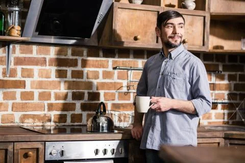 Nice bearded man drinking tea in the kitchen Stock Photos