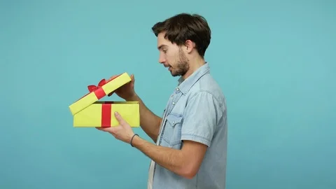 Nice bearded man unwrapping gift and expressing disappointment, showing thumbs Stock Footage 126074031
