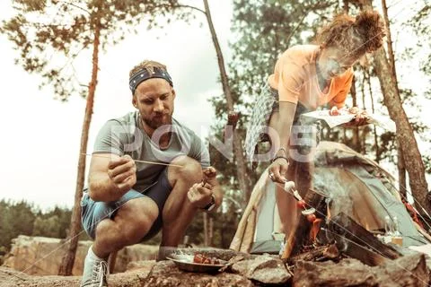 Nice bearded young man grilling delicious sausages Stock Photos