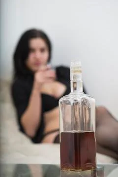 Nice bottle of whiskey on the table and sexy girl in black provocative linger Fotos Stock