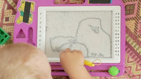 A nice boy of 2 years draws on a magnetic drawing board. He has great Stock Footage 78619503
