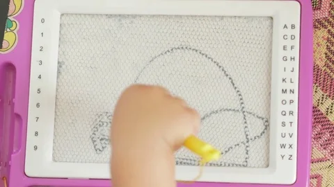 A nice boy of 2 years draws on a magnetic drawing board. He has great Stock Footage 78619736