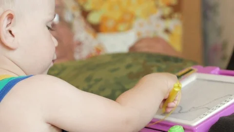 A nice boy of 2 years draws on a magnetic drawing board. He has great Stock Footage 78620055