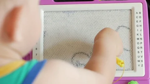 A nice boy of 2 years draws on a magnetic drawing board. He has great Stock Footage 78620245