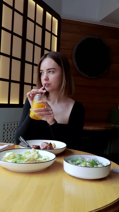 A nice brunette in a restaurant eats a dish of meat and chips with pleasure Stock Footage 285073023