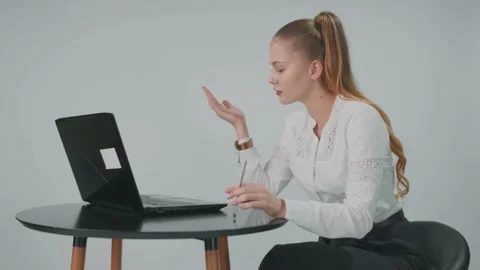Nice business lady is sitting at the table in the office and is speaking online Stock Footage 157936941