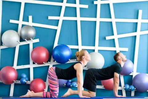 Nice couple doing yoga in a studio. Young people in yoga class in Cow pose. Y Foto stock