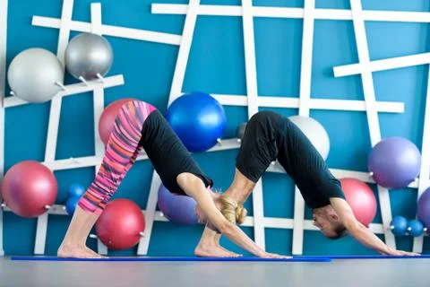 Nice couple doing yoga in a studio. Young people in yoga class in downward fa Foto stock