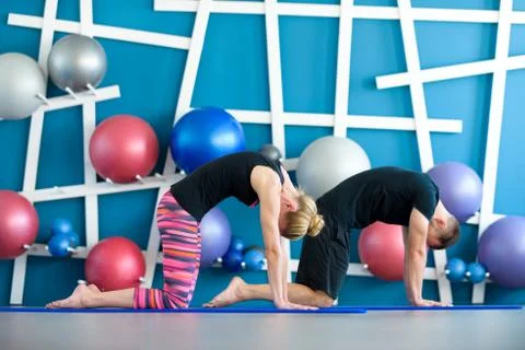 Nice couple doing yoga in a studio. Young people in yoga class in Cat pose. Y Stock Photos