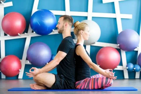 Nice couple doing yoga in a studio. Young people in yoga class in lotus posit Foto stock