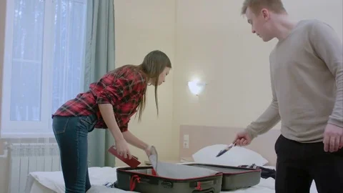 Nice couple packing their suitcase, putting clothes, having calls, taking selfie Vídeo Stock 73534340