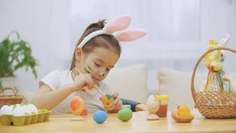 Nice, cute girl is having fun painting an Easter egg. Adorable girl is Stock Footage 104635932