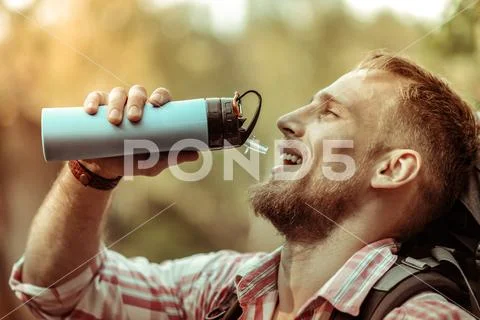 Nice delighted bearded man holding a thermos bottle Stock Photos