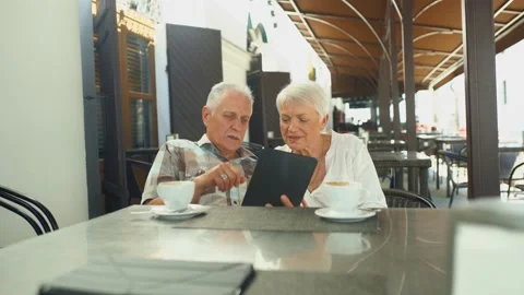 A nice elderly couple chooses dishes from the menu sitting at a table in a cafe Stock Footage 198716822