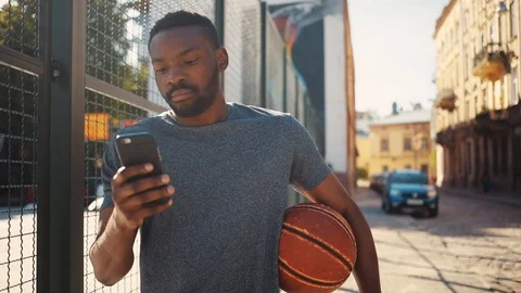 Nice focused African guy in gray T-shirt looking at screen of smartphone. Cute Stock Footage 92054816