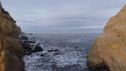 Nice forward-facing drone shot over the sea, passing between rocks at Huriawa Stock Footage 345346004