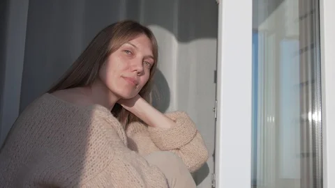 Nice girl basks in the spring sun during home quarantine Stock Footage 130134981