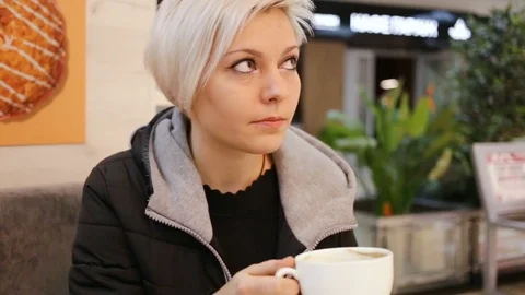 Nice girl drinking coffee from a Cup and turning one's mind to. Side view, close Stock Footage 85370977