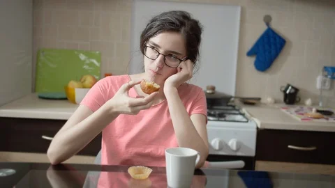 Nice girl sitting in the kitchen while having breakfast thinking Stock Footage 130126055