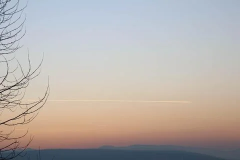 Nice gradient sunset with trace of plane. Stock Photos