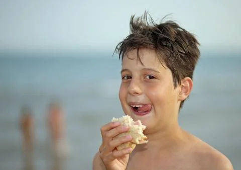 Nice guy while eating a sandwich on the beach in summer Фото