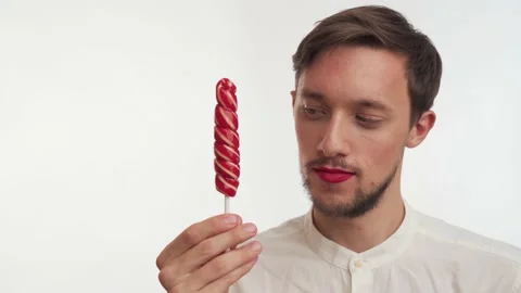 Nice handsome man with beard, moustache, hold sweet candy in hand, lick close up Stock Footage 147574650