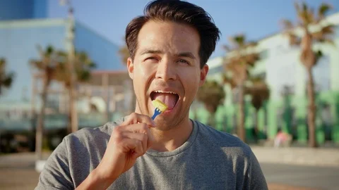 Nice healthy Hispanic guy eating joyfully fresh fruits standing at beach with Video stock 109419111