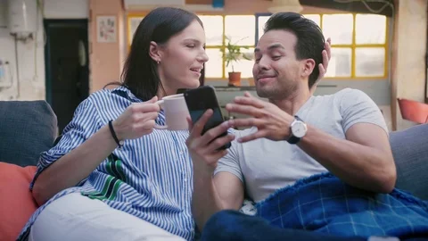 Nice Hispanic couple use new application on mobile device, enjoying to view Stock Footage 105759712