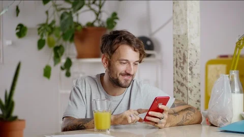Nice Hispanic guy using new application at morning time while drinking juice Stock Footage 108798246