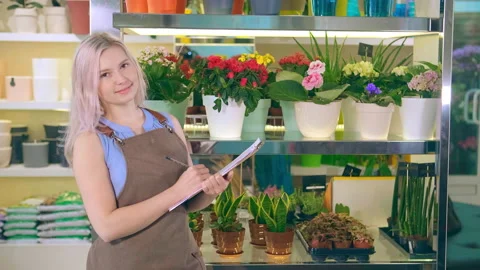 Nice lady holds black folder smiling against home plants 스톡 동영상 142510847