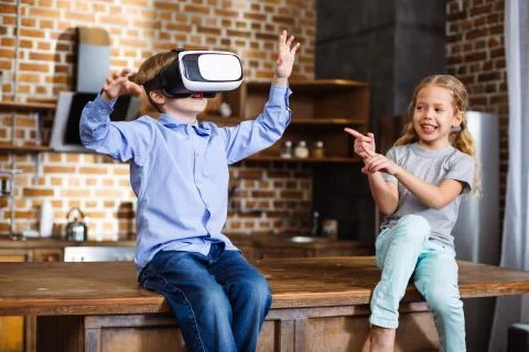 Nice little boy testing VR device with hi sister Stockfoto's