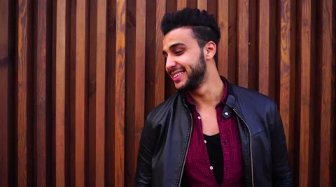 Nice-Looking Arabian Young Man Stands Near Wall and Smiles, Laughs, Looks at Stock Footage 68678246