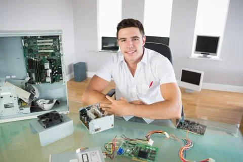 Nice looking computer engineer sitting at desk smiling at camera Stock Photos