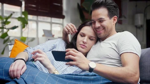 Nice lovely couple in cosy loft, watch film on smart phone device, spend leisure Stock Footage 105755682