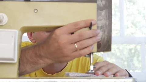 A nice man is sitting at the electric sewing machine at home. He sews several Video stock 78621664