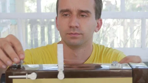 A nice man is sitting at the electric sewing machine at home. He sews several Stock Footage 78621827