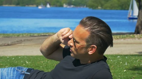 A nice man talks relaxed on a cellphone in a city park Stock Footage 89613929