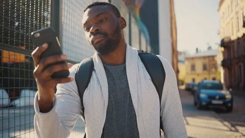 Nice modern guy in casual clothes walking in the street, using smartphone Stock Footage 92054004