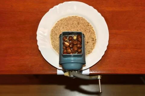 Nice old mill on a table with a plate. Milling nuts for baking sweet desserts Stock Photos
