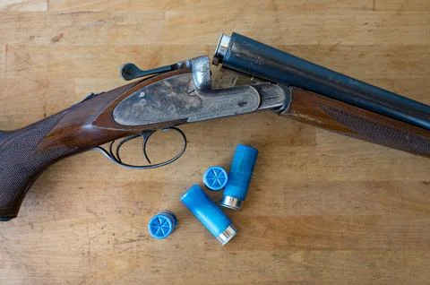 Nice old open parallel shotgun with some 12 gauge cartridges on a wooden table Stock-Fotos
