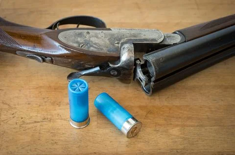 A nice old open parallel shotgun with some 12 gauge cartridges on a wooden table Stock-Fotos