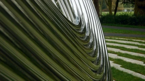 A nice part of forest is behind an abstract patterned shiny metal installation Stock Footage 105292836