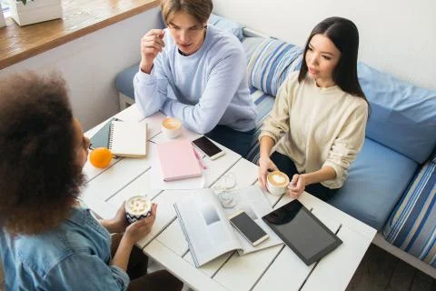 Nice picture of three students sitting at the table. There are lots of devices Stock Photos