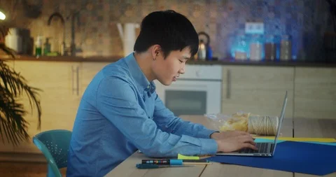 Nice pleasant Asian guy working using laptop alone typing on keyboard at home Stock Footage 124325932