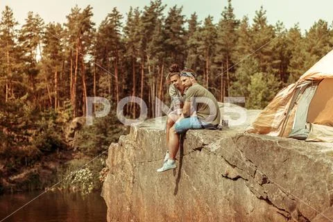 Nice pleasant couple sitting on a cliff Stock Photos