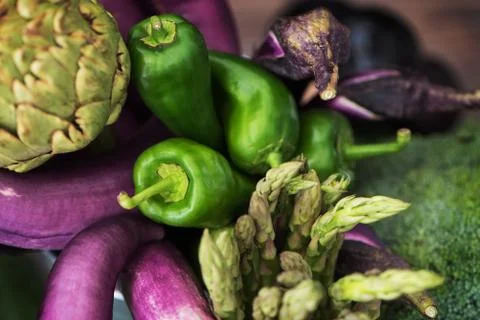 Nice raw vegetable still life of thin purple eggplants, green paprika peppers Stock Photos