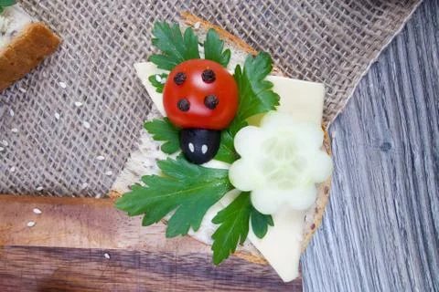 Nice red lady-bird on bread with vegetable on wooden board with napkin Stock Photos