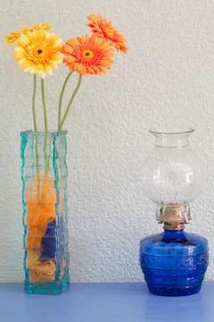 Nice rustic blue table with vase with orange and yellow flowers and an old lamp Stock Photos