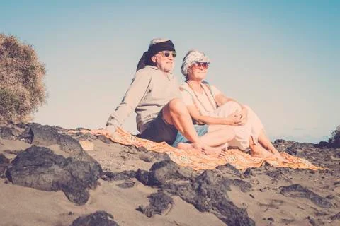 Nice senior couple sit down and enjoy the vacation at the rocky beach Stock Photos