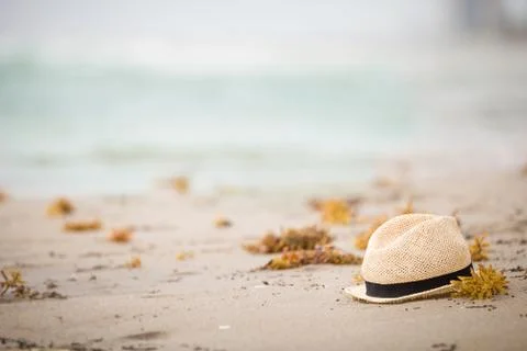 Nice straw hat laying on the sand. Beautiful ocean beach background. Outdoors Stock Photos
